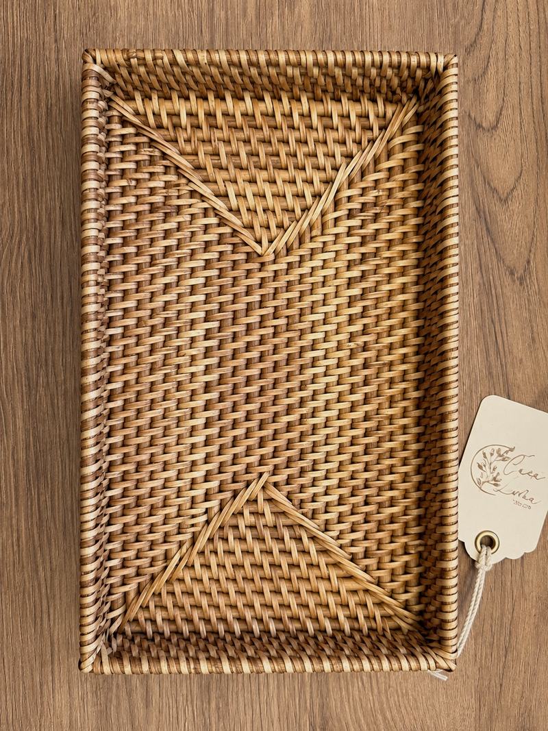 Bandeja rectangular de ratán tejido sobre una mesa de madera, con una etiqueta de Casa Luma.