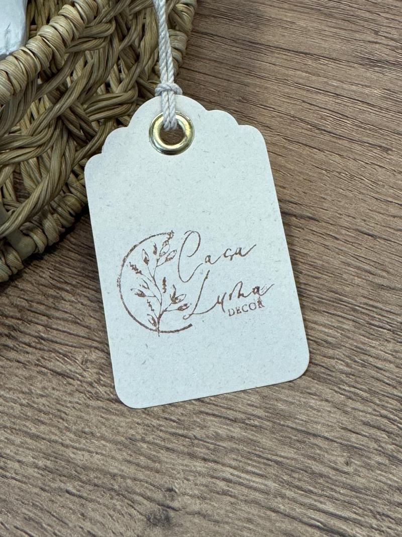 Etiqueta de papel con el logo de Casa Luma atada a una cesta de fibra natural sobre una mesa de madera.