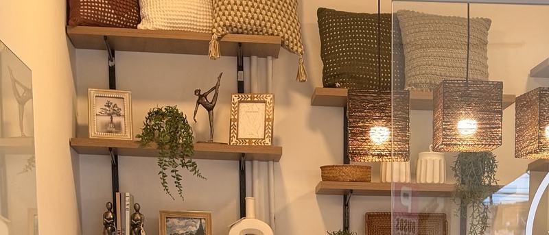 Interior de Casa Luma: estanterías de madera con cojines tejidos, marcos, figuras y cerámica blanca.