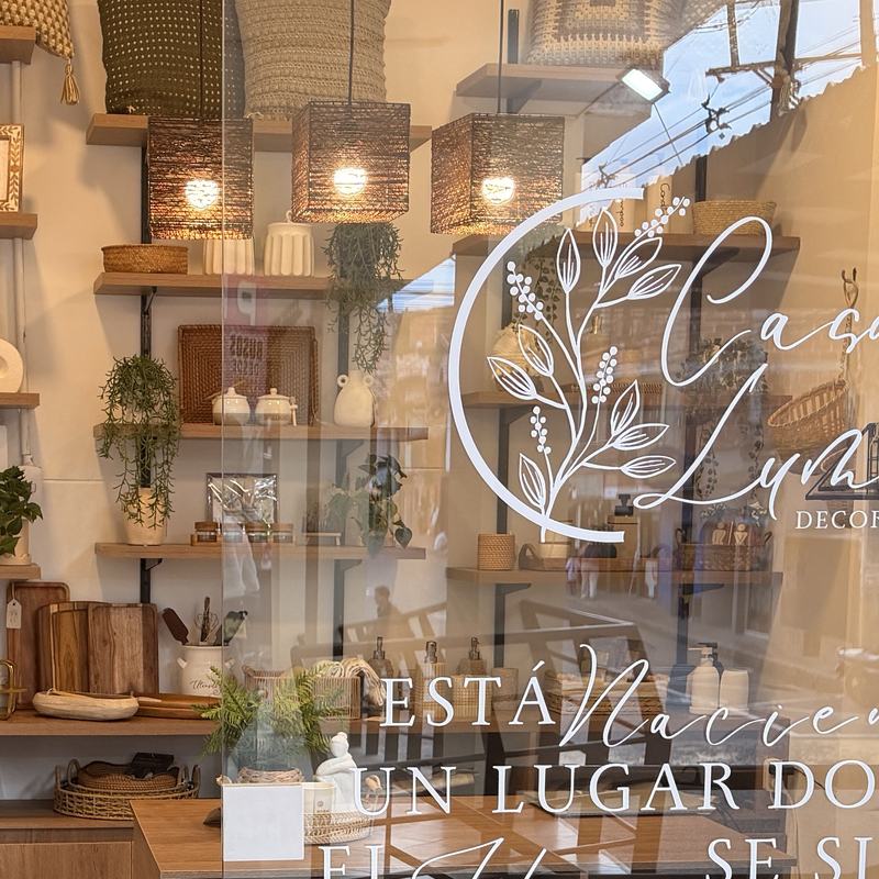 Detalle del logo de Casa Luma pintado en el vidrio de la vitrina, con lámparas de fibra encendidas detrás.